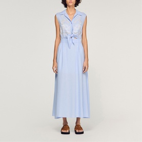 Model wearing Sandro Womens French Dress in sky blue, sleeveless shirt style with tie-front detail and midi length, styled with black sandals