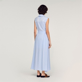 Model wearing Sandro Womens French Dress in sky blue, sleeveless midi length with collar and full skirt, back view, styled with black flat shoes.