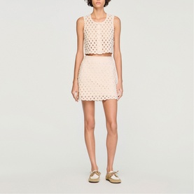 Model wearing Sandro clear eyelet crop top and mini skirt co-ord set, styled with metallic flat sandals