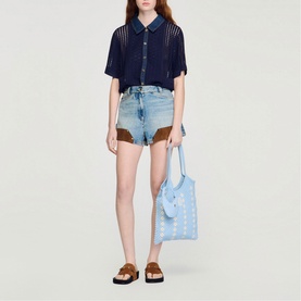 Model wearing Sandro navy blue sheer knit short-sleeve shirt with denim shorts, styled with a light blue tote bag and brown sandals.