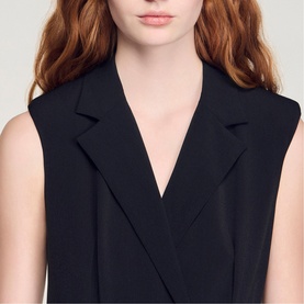 Model wearing Sandro Womens French Dress in black, featuring a sleeveless silhouette with a notched lapel and wrap-style V-neckline.
