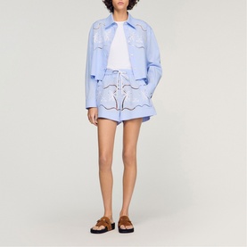 Model wearing Sandro sky blue embroidered shorts with drawstring waist, styled with matching jacket and white tee