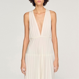 Model wearing Sandro Womens French Dress in clear, sleeveless deep V-neck pleated midi dress in ivory tones