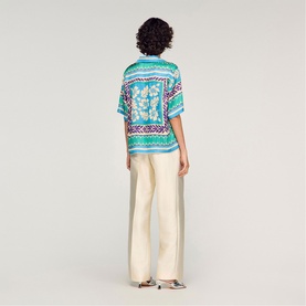 Model wearing Sandro green and purple printed short-sleeve shirt, styled with cream wide-leg trousers, rear view.
