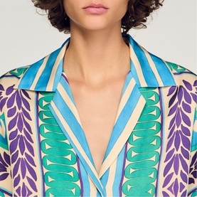 Model wearing Sandro green and purple geometric print shirt with open collar, featuring teal stripe and leaf pattern detailing