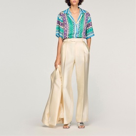 Model wearing Sandro green and purple printed short-sleeve shirt, styled with cream wide-leg trousers and white sandals.