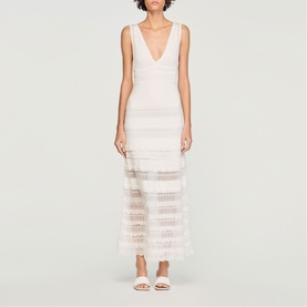 Model wearing Sandro Womens French Dress in clear white, sleeveless maxi with deep V-neck, sheer stripe panels, styled with white flat sandals