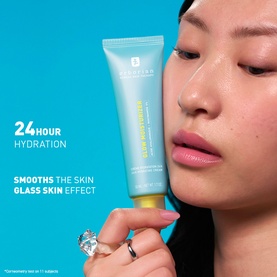 Model holding Erborian Glow Moisturiser light blue tube close to face, showcasing 24-hour hydration and glass skin effect claims