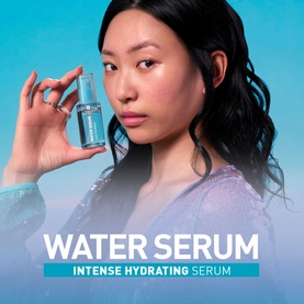 Model with Erborian Water Serum, holding clear glass bottle of intense hydrating serum against blue background