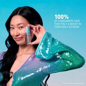 Model with Erborian Water Serum held up to face, wearing a teal sequin dress against a blue background