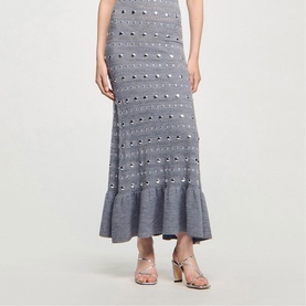 Model wearing Sandro black embellished midi skirt with ruffle hem, styled with nude heeled sandals