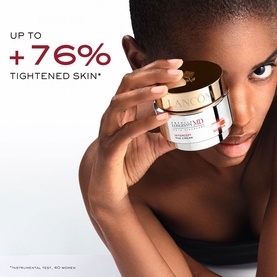 Model with Lanc&ocirc;me Absolue Longevity Intercept Cream jar, gold lid, held close to face against white background with +76% tightened skin claim