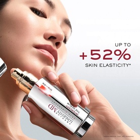 Model with Lanc&ocirc;me Absolue Longevity Intercept Serum held close to face, featuring gold-tipped dropper bottle with up to +52% skin elasticity claim.