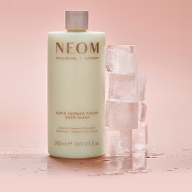 Neom Organics Super Shower Power Body Wash, sage green 500ml bottle styled with melting ice cubes on pink background