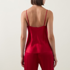 Model wearing Simone Perele silk camisole top in Opera Red, back view showing low open back and thin straps, styled with matching red trousers