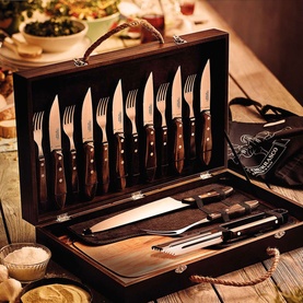 Tramontina brown wooden presentation case containing steak knives, carving knife, fork and serving utensils, styled on a rustic table