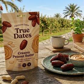 True Dates Creamy Peanut Butter Flavoured Dates pouch on wooden table, styled with dates on a plate and coffee cup in garden setting.