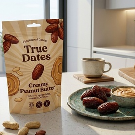 True Dates Creamy Peanut Butter Flavoured Dates pouch on kitchen counter, with dates and peanut butter dip styled on a plate nearby.