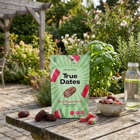 True Dates Sour Watermelon flavoured dates in green resealable pouch, styled on garden table with fresh dates and herbs