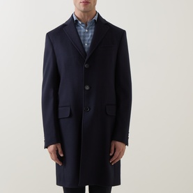Model wearing Zegna navy blue wool cashmere coat with notched lapels and three-button front, styled with blue check shirt.