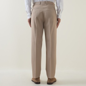 Model wearing Zegna Formal Slim-Leg Trousers in light taupe, rear view showing pressed creases, rear jetted pockets and belt loops, styled with white