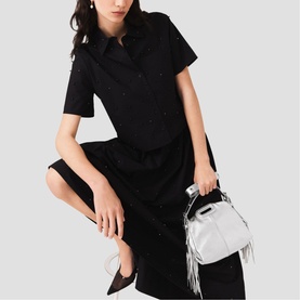 Model carrying Maje bag in silver with fringe detail and top handle, styled with a black midi shirt dress