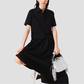 Model wearing Maje red short-sleeve shirt and midi skirt with broderie anglaise detailing, styled with a silver fringed bag