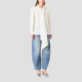 Model wearing Maje metallic top with tie neck detail, styled with blue barrel-leg jeans and silver heeled mules