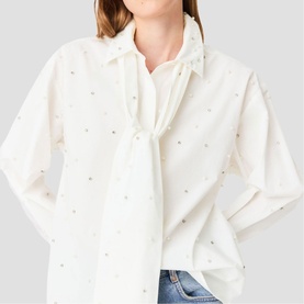 Model wearing Maje metallic embellished white blouse with tie neck detail, styled with blue jeans