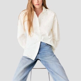Model wearing Maje metallic embellished white oversized shirt, styled with light blue wide-leg jeans