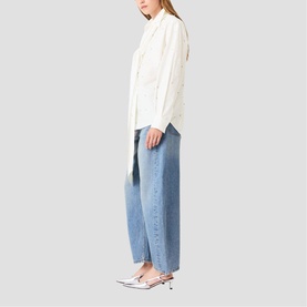 Model wearing Maje metallic white broderie shirt with light wash barrel-leg jeans and silver pointed kitten heel mules