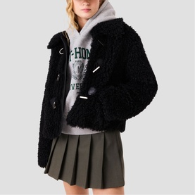 Model wearing Maje red cropped teddy fleece jacket with toggle fastenings, styled with grey graphic hoodie and khaki pleated mini skirt