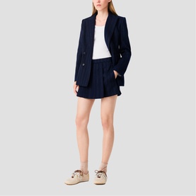 Model wearing Maje navy blazer and matching shorts, styled with a white top and beige lace-up shoes