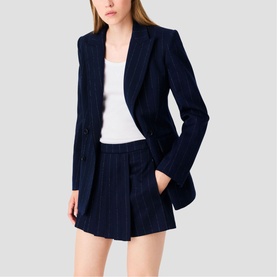 Model wearing Maje navy pinstripe blazer and matching shorts, styled with a white top