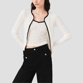 Model wearing Maje metallic white knit cardigan with black contrast trim, styled with matching crop top and black wide-leg trousers