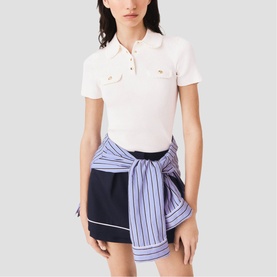 Model wearing Maje metallic polo top with chest pockets, styled with navy mini skirt and striped shirt tied at waist