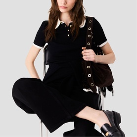 Model wearing Maje red knit polo dress with white collar trim, styled with black wide-leg trousers, carrying dark suede fringed shoulder bag
