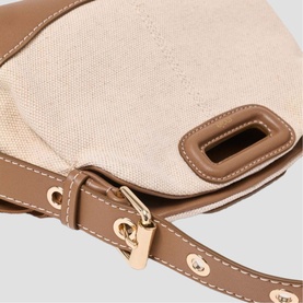Maje bag in canvas and tan leather with gold-tone hardware and adjustable strap, close-up detail view