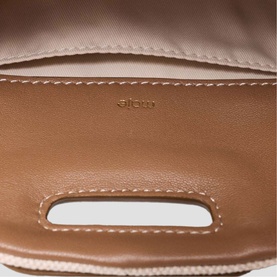 Maje bag interior lining in tan with contrast stitching and branded stamp detail, shown with slot opening visible.