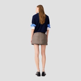 Model wearing Maje multi check mini skirt, styled with navy knit, blue shirt and black loafers, rear view