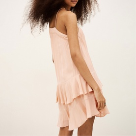 Model wearing Bash pink sleeveless mini dress with tiered ruffle hem and spaghetti straps, shown from the back