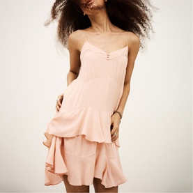 Model wearing Bash pink strappy mini dress with tiered ruffle hem and button-front bodice detail