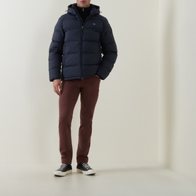 Model wearing Gant Evening Blue puffer jacket with hood, styled with rust chinos and black high-top trainers.