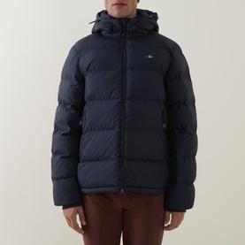 Model wearing Gant Evening Blue hooded puffer jacket with zip pockets, styled with burgundy trousers.