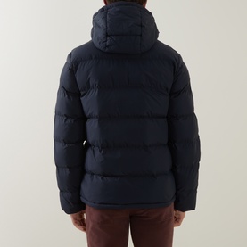 Model wearing Gant Evening Blue hooded puffer jacket, rear view, styled with burgundy trousers.