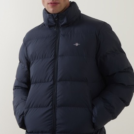 Model wearing Gant Evening Blue quilted puffer jacket with stand collar, zip fastening, and embroidered logo chest badge.