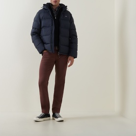 Model wearing Gant Evening Blue casual puffer jacket with hood, styled with rust-brown trousers and black high-top trainers.
