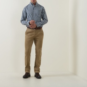 Model wearing Gant light taupe cotton chino trousers, styled with a blue check shirt and brown leather belt and shoes.