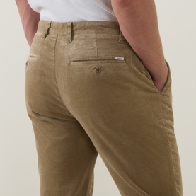 Model wearing Gant light taupe cotton chino trousers, close-up of rear pocket and belt loop detail, styled with white top.