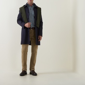 Model wearing Gant light taupe cotton chino trousers, styled with a navy coat, green gilet, and checked shirt.